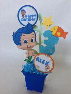 a blue cup with a little boy in it and some decorations on the top that says happy birthday alex