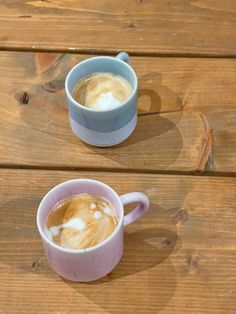 two cups of coffee sitting on top of a wooden table