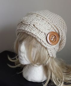 a mannequin head wearing a white knitted hat with a wooden button on it