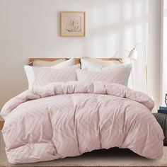 a bed with pink comforter and pillows in a room