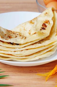 there is a white plate with some bread on it and eggs in the background,