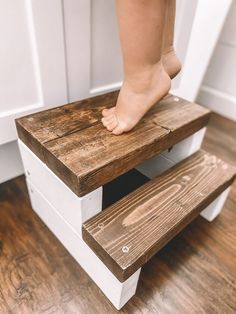 a child's foot stepping up and down a wooden step stool with white painted steps