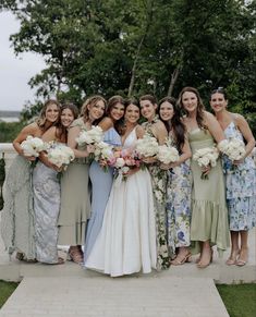 a group of women standing next to each other holding bouquets in front of them