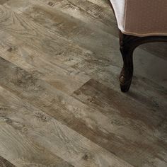 a wooden floor with a chair and table in the background