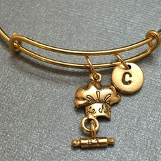 A chef hat charm bangle bracelet with hand stamped initial *Bracelet is adjustable *Initial charm is antique gold pewter 9mm *Chef hat charm is antique gold pewter *Your purchase will arrive packaged in a cute gift box and I will include a message by request. Add on a birthstone charm for $3.00 https://www.etsy.com/listing/235600956 Additional Hand stamped initial charm $3.50 https://www.etsy.com/listing/232868096 *Go back to Toodaughters https://www.etsy.com/shop/Toodaughters Bracelet Initial, Chef Hat, Cute Gift Boxes, Personalized Bracelet, Chefs Hat, A Chef, Bangle Bracelets With Charms, Initial Bracelet, Personalized Bracelets