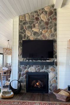 a stone fireplace with a flat screen tv mounted above it and a rug on the floor