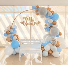 a white bench sitting in front of a balloon arch with blue and gold balloons on it