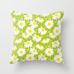 a green and white pillow with daisies on it