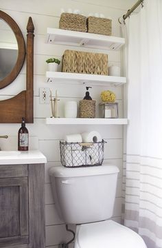 a white toilet sitting in a bathroom next to a wooden sink vanity and wall mounted mirror