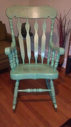 a green rocking chair sitting on top of a hard wood floor