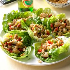 lettuce wraps filled with chicken and vegetables on a plate next to a bottle of beer