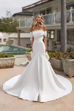 a woman in a white wedding dress standing on the ground next to a palm tree