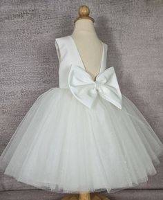 Elegant  glitter tulle flower girl dress for special occasions:  Off white flower girl dress.    Tulle  baby dress sewn by hand from the highest quality fabrics.   *Top of the  girl dress: satin, cotton inside.  *  Tulle skirt;   tulle, glitter tulle,  satin, lining with crinoline for fullness.   * detachable satin  bow *color off white *Knee  or tea length.   Dress comes in different sizes, please make sure to check the measurements below before placing your order. Available dresses according to customer dimensions Tulle Flower Girl Dress, Tulle Flower Girl, White Flower Girl Dresses, Tulle Flowers, Flower Girl Dresses Tulle, Flower Girl Dress, Tea Length, Tea Dress, White Flower