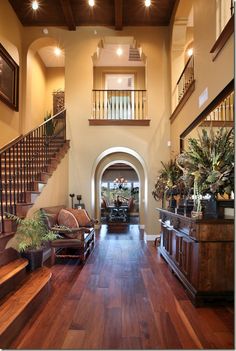 a living room filled with furniture and lots of wood flooring next to a stair case