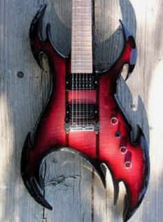 a red electric guitar sitting on top of a wooden fence