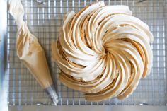 a cake with frosting on top sitting on a cooling rack next to a pastry knife