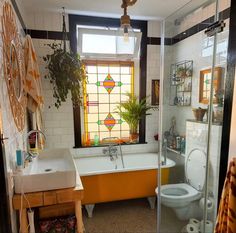 a bath room with a toilet a sink and a bath tub next to a window