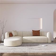 a living room with a large white couch and round ottoman on the floor in front of a window