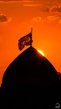 the sun is setting behind a building with a flag on top and an orange sky in the background