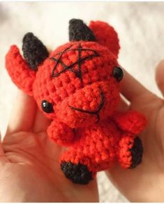 a small crocheted red and black animal in someone's hand