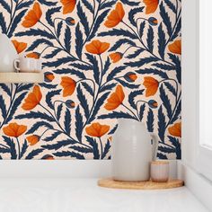 an orange and blue floral wallpaper with white vases on the counter next to it