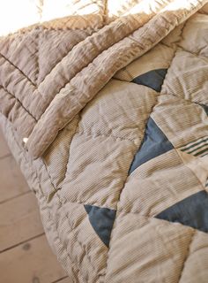 a close up of a bed with a quilted cover on it's side