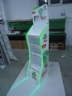 an open cardboard display case with neon green lights on the bottom and sides, in a workshop area