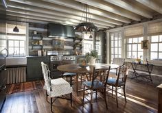 a kitchen and dining room with wood floors, white walls and wooden beams on the ceiling