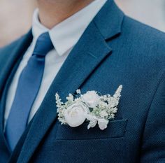 a man wearing a blue suit and white flowers on his lapel