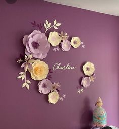 a purple wall with paper flowers and the word grandma written in cursive writing