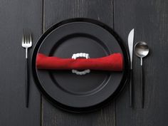 a black plate topped with a red napkin and silverware