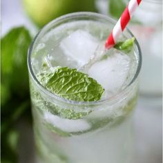 two glasses filled with ice and mint on top of a table