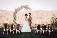 a bride and groom standing next to each other in front of rows of gold chairs