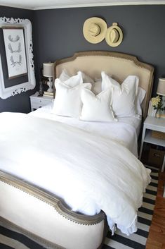 a bed with white linens and pillows in a small room next to a mirror