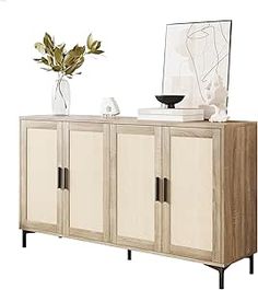 a sideboard with three doors and two vases on the top one has a plant in it