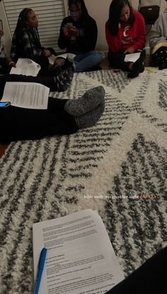 several people sitting on the floor with papers in front of them