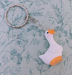 a rubber duck keychain sitting on top of a flowered tablecloth covered floor