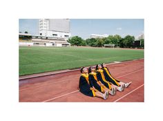 four graduates sitting on the side of a track