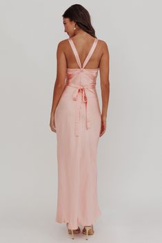 the back of a woman wearing a pink dress with a bow at the waist and straps