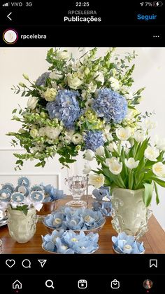 a vase filled with blue and white flowers on top of a table next to plates