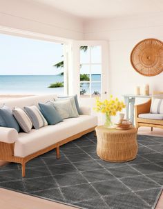 a living room filled with furniture and a large window next to the ocean in front of it