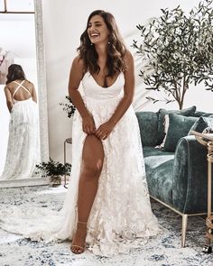 a woman in a white dress sitting on a couch next to a mirror with her legs crossed