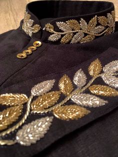 an embroidered jacket with gold leaves on the collar and side buttons is seen in this close up photo