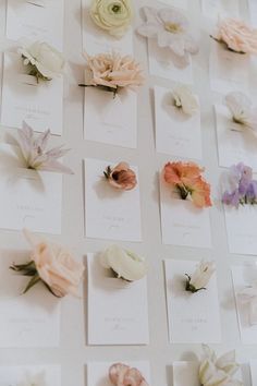 many different types of flowers are arranged on the white tablecloth with cards and envelopes