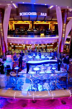 the inside of a cruise ship with many tables and chairs in front of it, all lit up at night