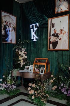 a green room with pictures and flowers on the wall next to a table in front of it