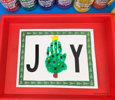 a red tray with a handprinted christmas tree on it and some jars of jelly beans in the background