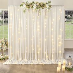 a white curtain with flowers and candles in front of it