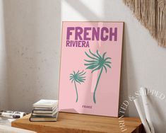 a french riviera poster sitting on top of a table next to a stack of books