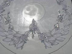 a white table cloth with beads and leaves on it